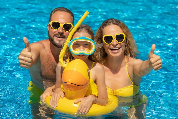 Happy family playing in outdoor pool People having fun on summer vacation Healthy lifestyle concept