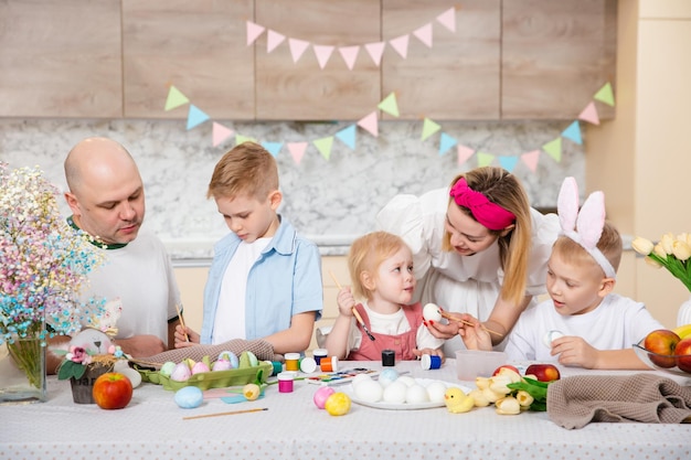 Happy Family preparing for Easter Cute children painting eggs Home activity Concept of unity and love Mom dad son daughter Brothers and sister