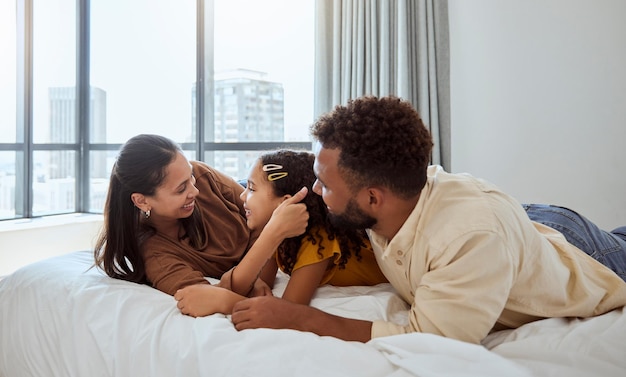 Happy family relax and girl in bed with mother and father bond and resting in their home together Love black family and child enjoy lazy morning indoors with parents rest and embrace in bedroom