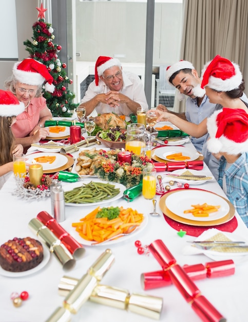 Happy family in santas hats enjoying Christmas dinner