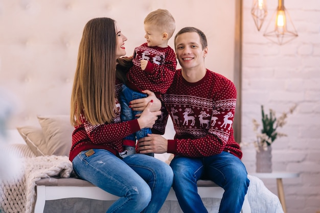 Happy family sitting on bed. Christmas tree near the bed.