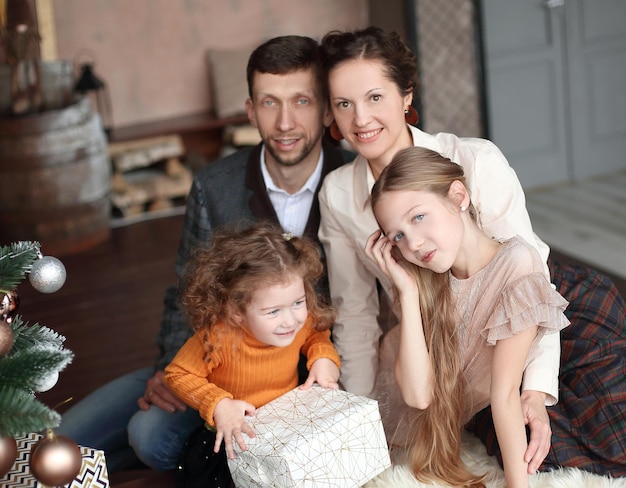 Happy family sitting near the christmas tree in the cozy living room