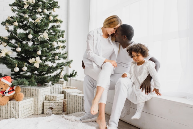 Happy family sitting near the Christmas tree