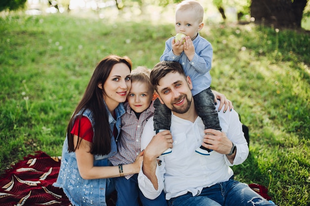 Happy family sitting in park together with kids, embracing