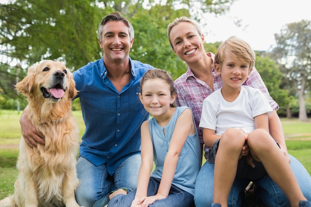 Happy family smiling at the camera with their dog