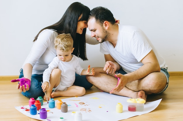 happy family son with parents painting a poster 