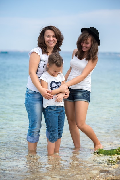 Happy family standing on a wood pontoon in front of the sea in summertime