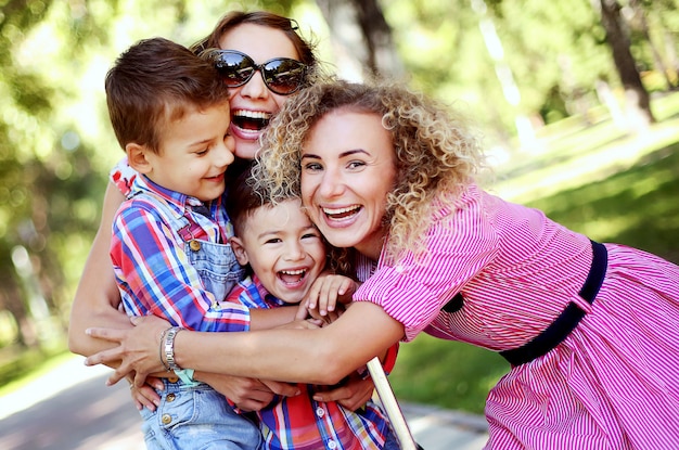 Happy family in summer park. Women and children hugging and smiling.