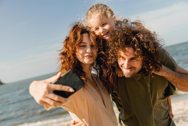 Happy family taking selfie and spending good time at the beach together