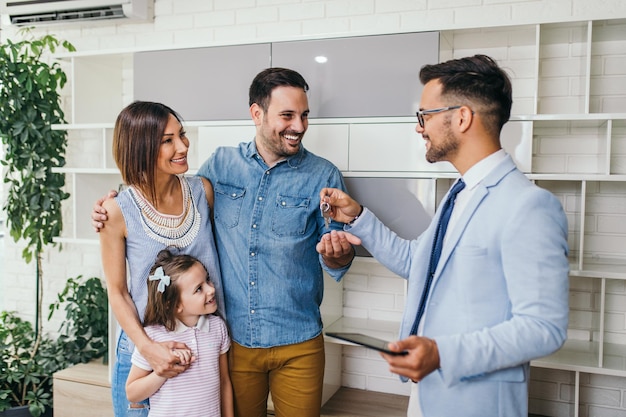 Happy family talking a key of their new home from with real estate agent.