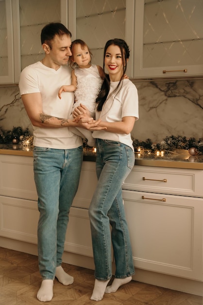 A happy family of three in jeans and white Tshirts poses in New Years locations