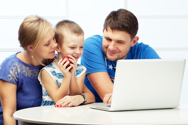 Happy family of three at the table with a computer