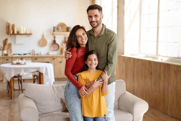 Happy family of three with preteen daughter posing at home