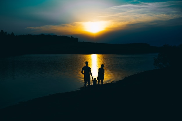 Happy family together, parents with their little child at sunset. Father raising baby up in the air