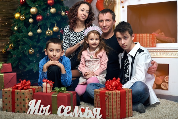 Happy family at the tree by the fireplace. Mom, dad and three kids on winter vacation. Christmas eve and New year's eve.