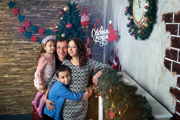 Happy family at the tree by the fireplace. Mom, dad and two kids on winter vacation. Christmas eve and New year's eve.