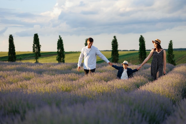 Happy family walking in lavender field with beautiful scenery in the background