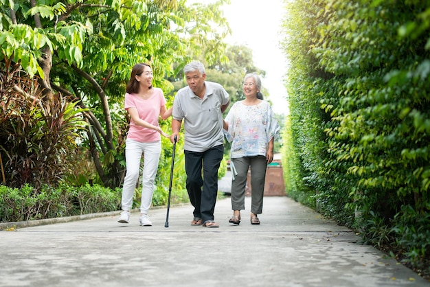 Happy family walking together in the garden Old elderly using a walking stick to help walk balance Concept of Love and care of the family And health insurance for family