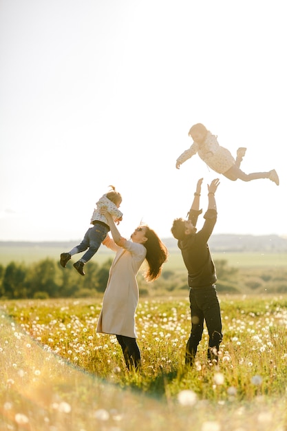 Happy family walks in nature. Mom and Dad throw their children