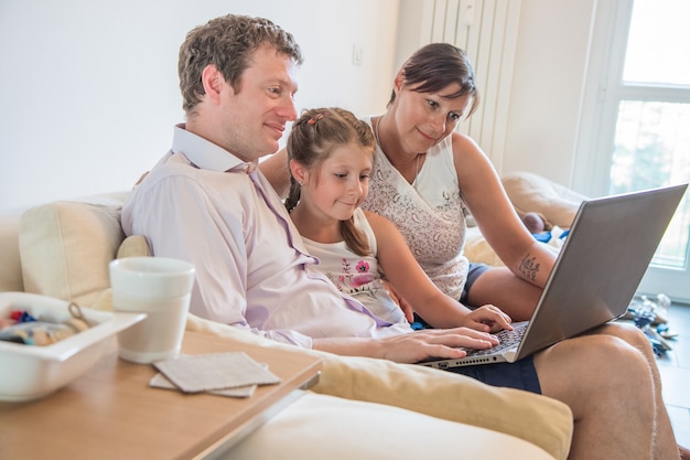 Happy family watch the pc sitiing on the sofa