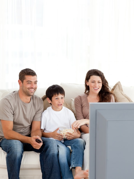 Happy family watching television while eating popcorn together