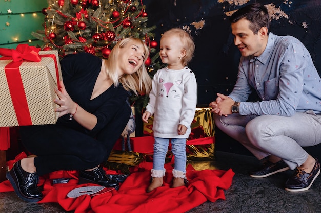 Happy family with a child celebrate the new year near the Christmas tree