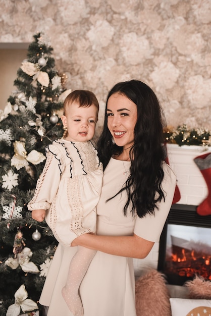 Happy family with child celebrating New Year and Christmas at decorated Christmas tree and garlands