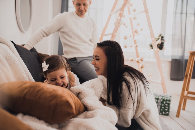 Happy family with child celebrating New Year and Christmas at decorated Christmas tree and garlands