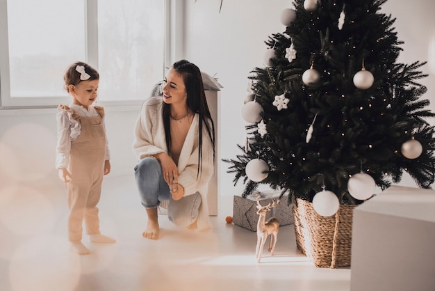 Happy family with child celebrating New Year and Christmas at decorated Christmas tree and garlands