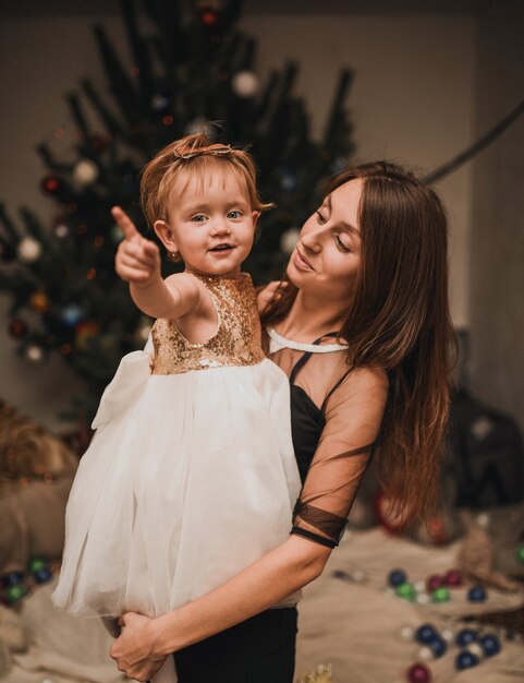 Happy family with child celebrating New Year and Christmas at decorated Christmas tree and garlands