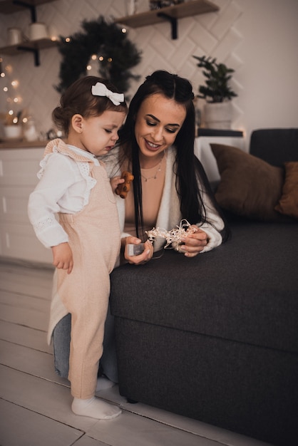 Happy family with child celebrating New Year and Christmas at decorated Christmas tree and garlands