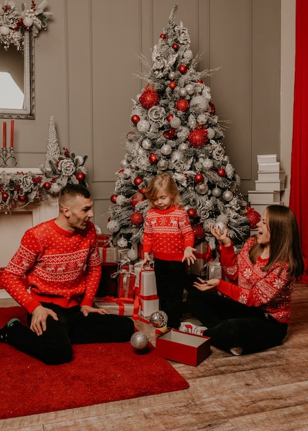 Happy family with child celebrating New Year and Christmas at decorated Christmas tree and garlands