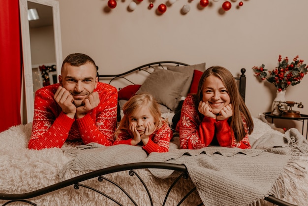 Happy family with child celebrating New Year and Christmas at decorated Christmas tree and garlands