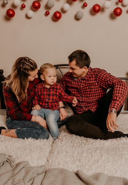 Happy family with child celebrating New Year and Christmas at decorated Christmas tree and garlands