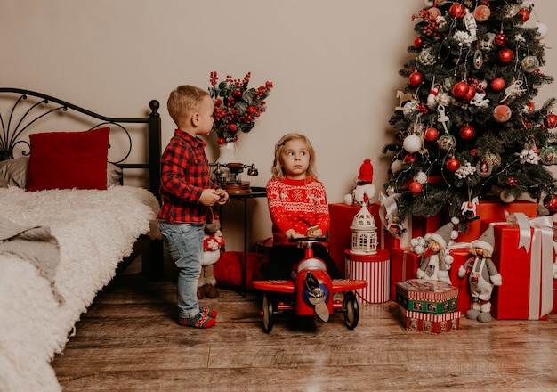 Happy family with child celebrating New Year and Christmas at decorated Christmas tree and garlands