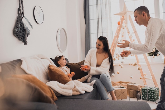 Happy family with child celebrating New Year and Christmas at decorated Christmas tree and garlands