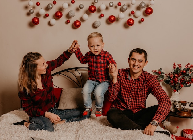 Happy family with child celebrating New Year and Christmas at decorated Christmas tree and garlands