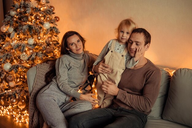 Happy family with a child at home near the Christmas tree are waiting for the New Year