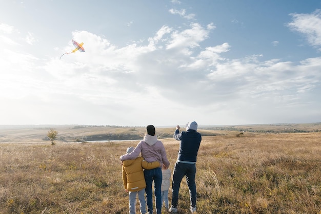 A happy family with children flies a kite and spends time together outdoors in a nature reserve Happy childhood and family holidays Freedom and space