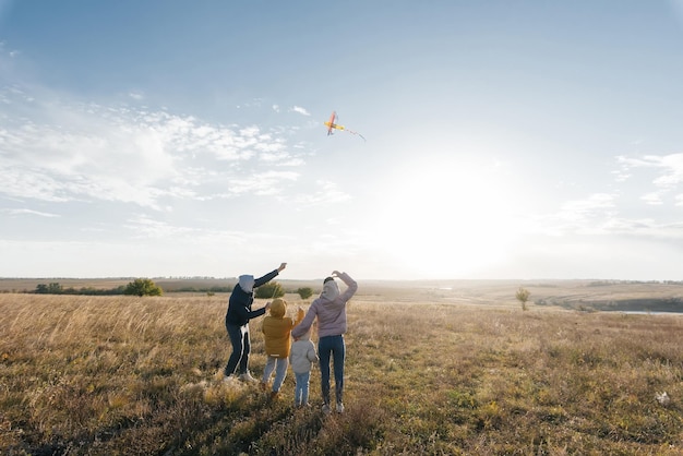 A happy family with children flies a kite and spends time together outdoors in a nature reserve Happy childhood and family holidays Freedom and space