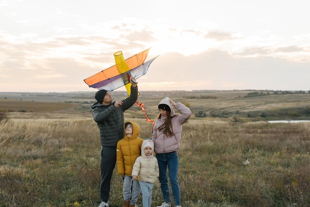 A happy family with children flies a kite and spends time together outdoors in a nature reserve Happy childhood and family holidays Freedom and space