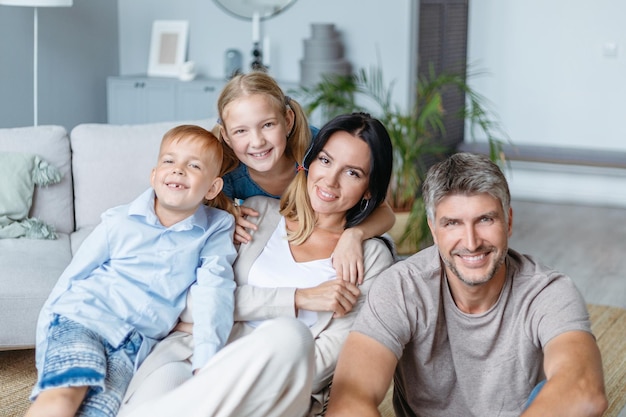 Happy family with children sitting on the floor in the living room