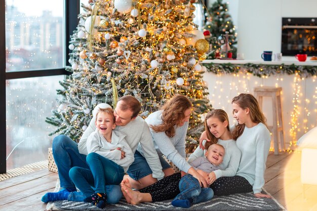 Happy family with four sibilings near the Christmas tree with the present boxes. Christmas family morning, christmas mood concept