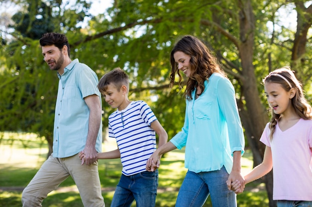 Happy family with hand in hand walking in park