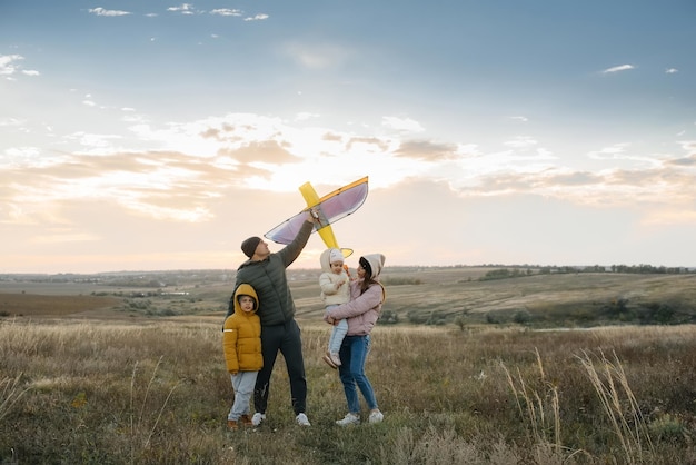 A happy family with kids launches a kite and spends time together in the fresh air. Happy childhood and family holidays.