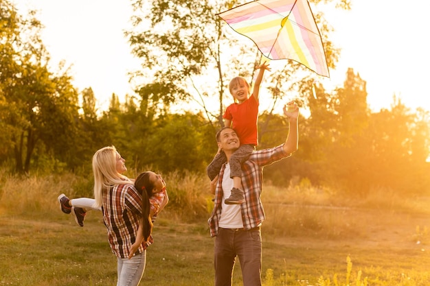 Happy family with a kite playing at sunset in the field