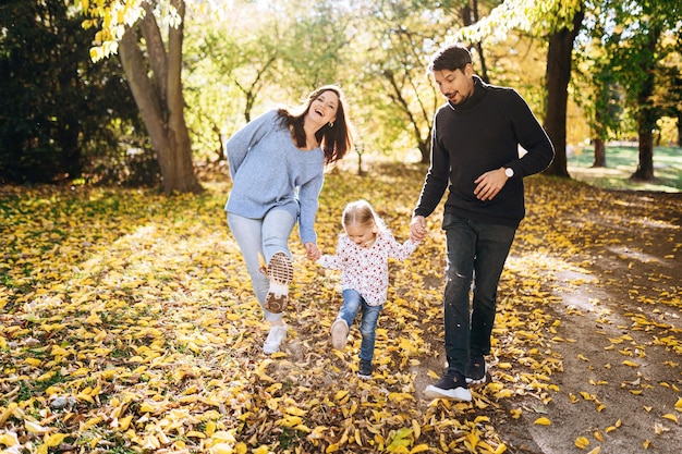 Happy family with little daughter in autumn park outdoor recreation