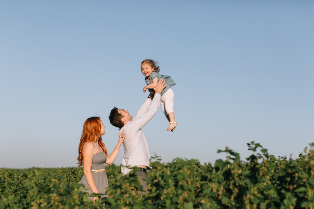 Happy family with little daughter spending time together in the sunny field