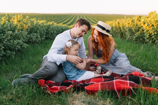 Happy family with little daughter spending time together in the sunny field