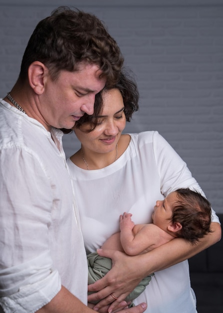 Happy family with a newborn baby Loving mother and father tenderly hold their son in their arms